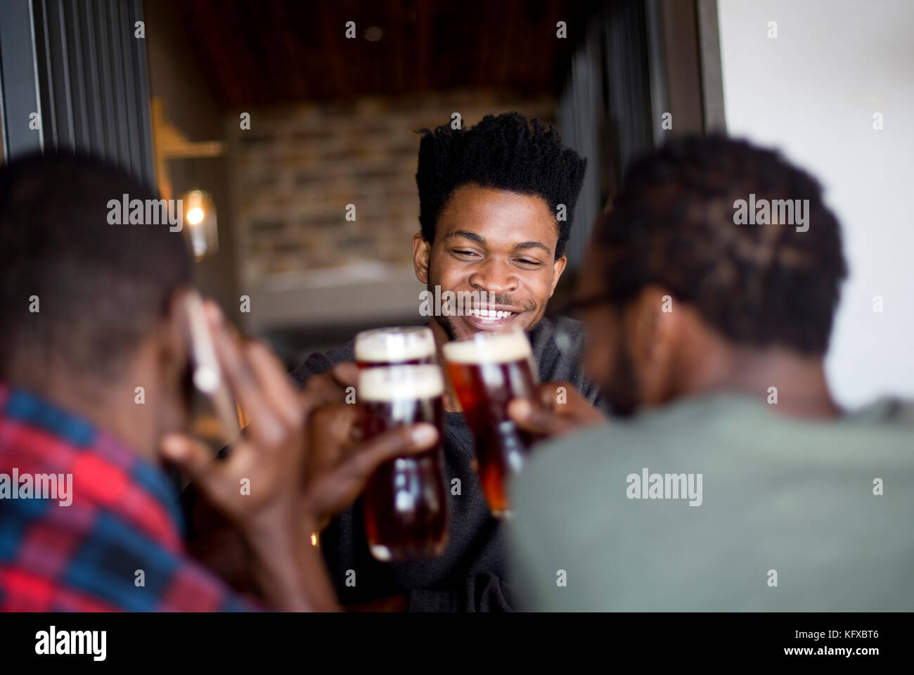 Three men toasting at a bar Stock Photo