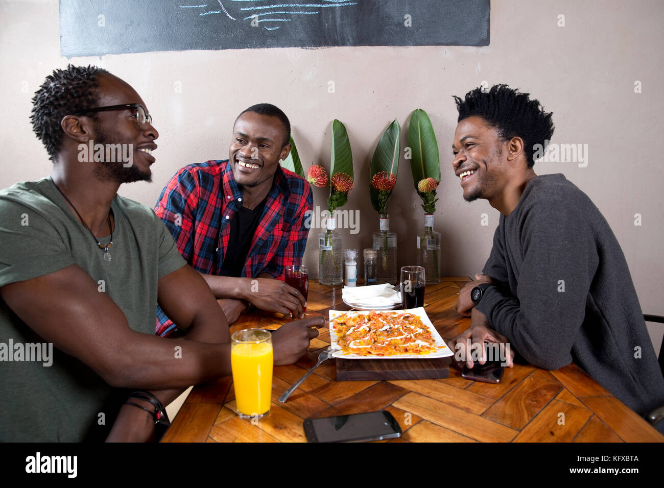 Three men eating nachos at a restaurant Stock Photo