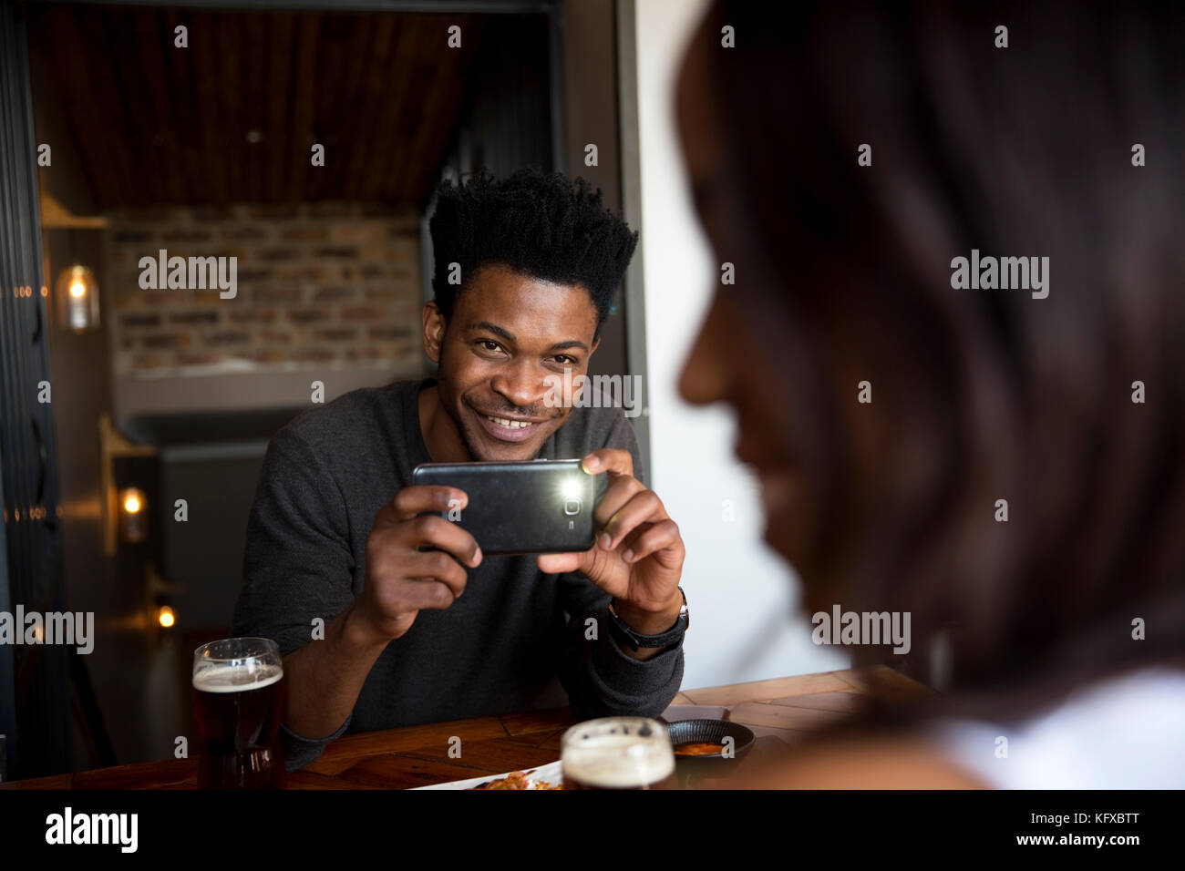 Man taking a photo of his date with a smartphone Stock Photo