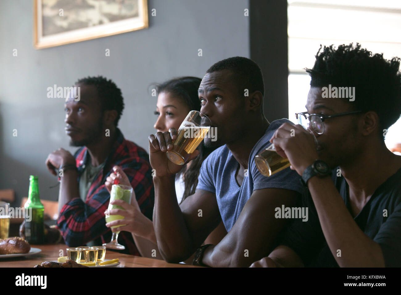 Friends watching television in sports bar Stock Photo