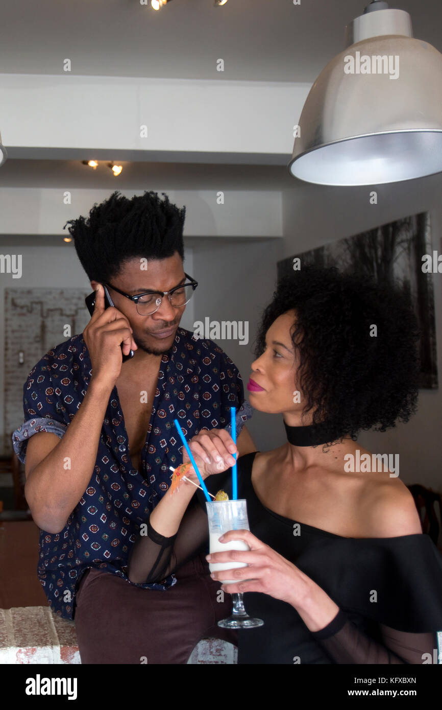 Man talking on the phone and woman drinking a cocktail Stock Photo