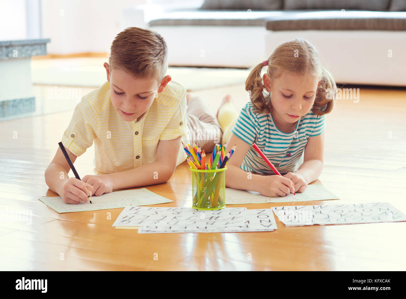 Two cute children draws with colorful pencils on the floor at home ...