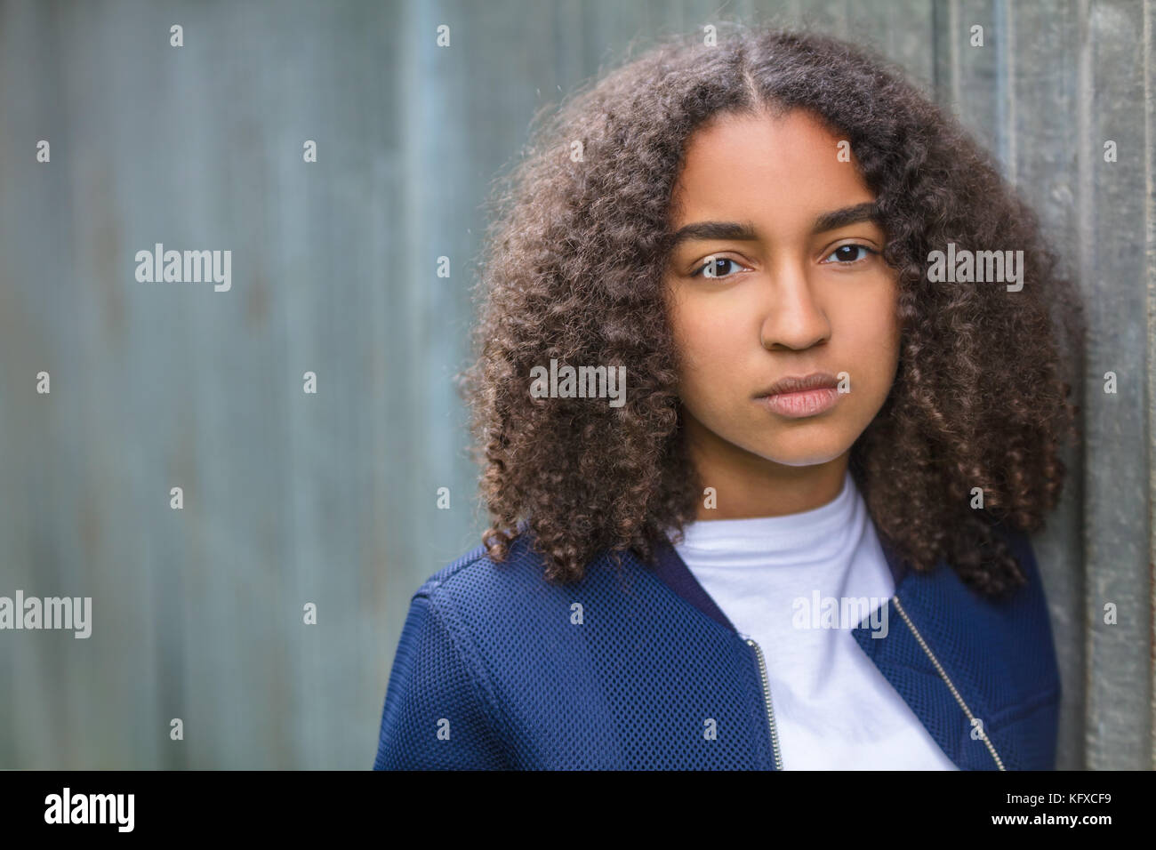 Beautiful mixed race African American girl teenager female young woman outside looking sad depressed or thoughtful Stock Photo