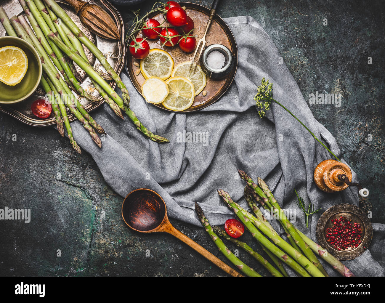 Asparagus with wooden spoon and cooking ingredients, preparation on dark rustic background, top view, frame Stock Photo