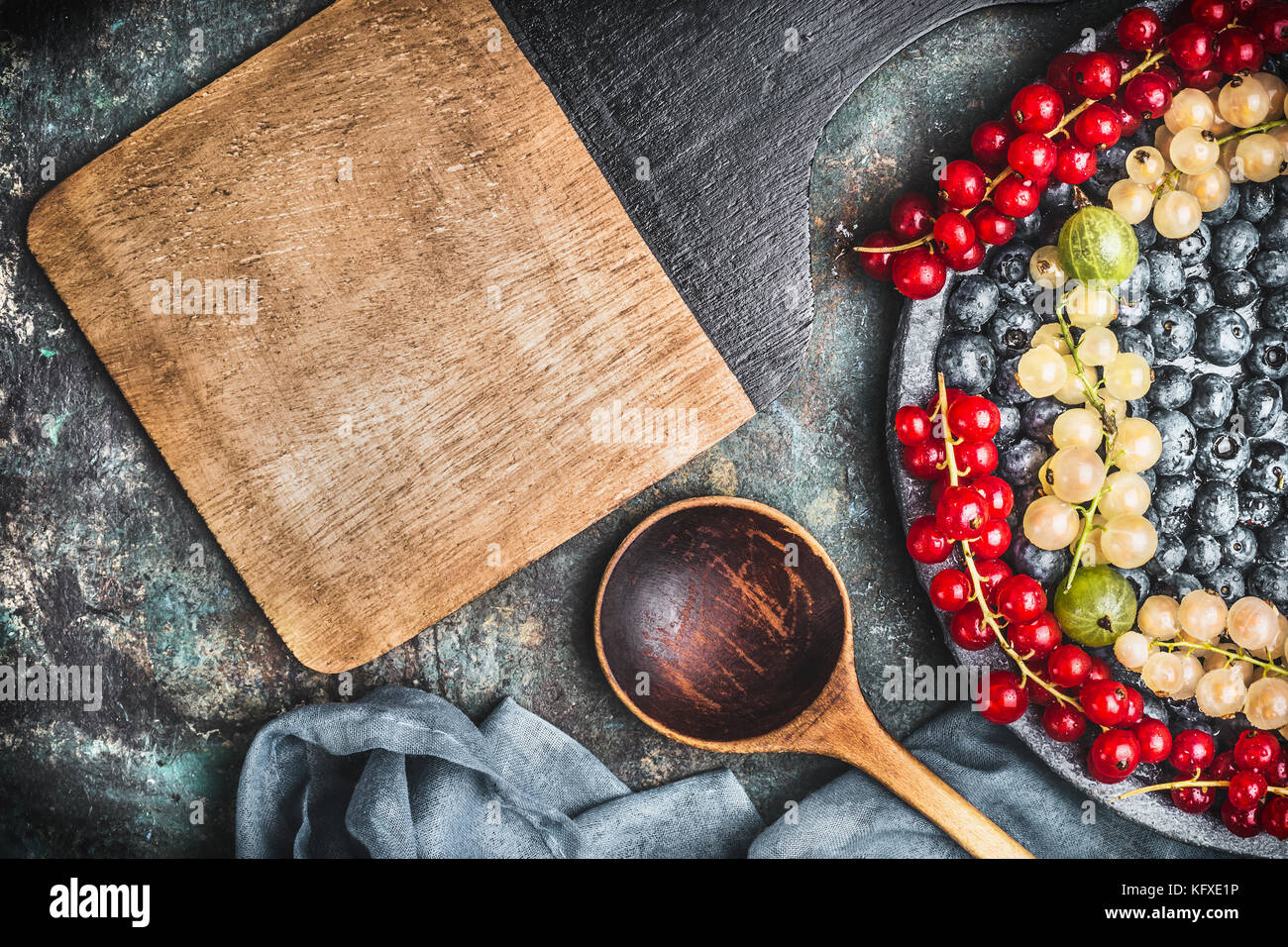 Food background for healthy recipes with various colorful berries,  cooking spoon, bowls and napkin , top view , frame Stock Photo