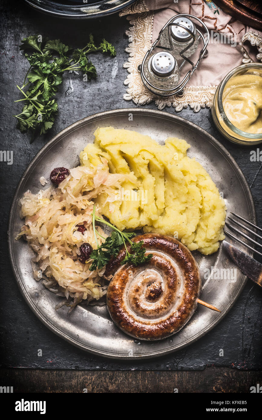 Roasted sausage with Mashed Potatoes and pickled cabbage in metal plate with cutlery served on