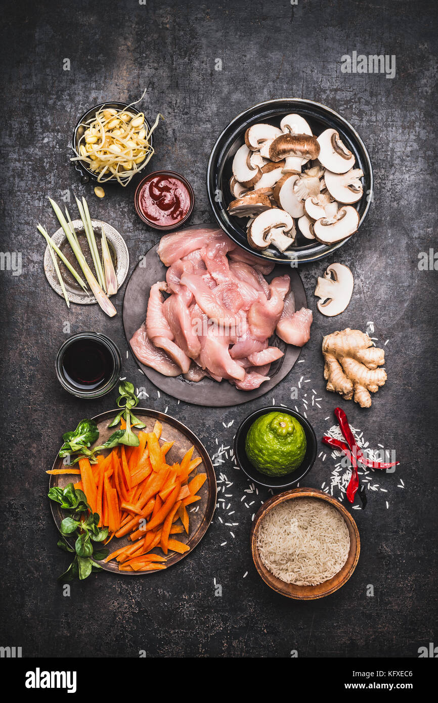 Asian cooking ingredients for chicken rice dish with vegetables on dark rustic background , top view, flat lay Stock Photo