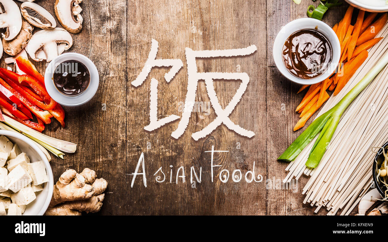 Asian food with various vegetables cooking ingredients on wooden background with Chinese hieroglyph of food, top view, banner Stock Photo