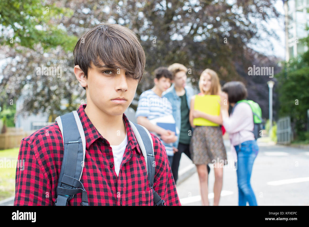 Unhappy Boy Being Gossiped About By School Friends Stock Photo