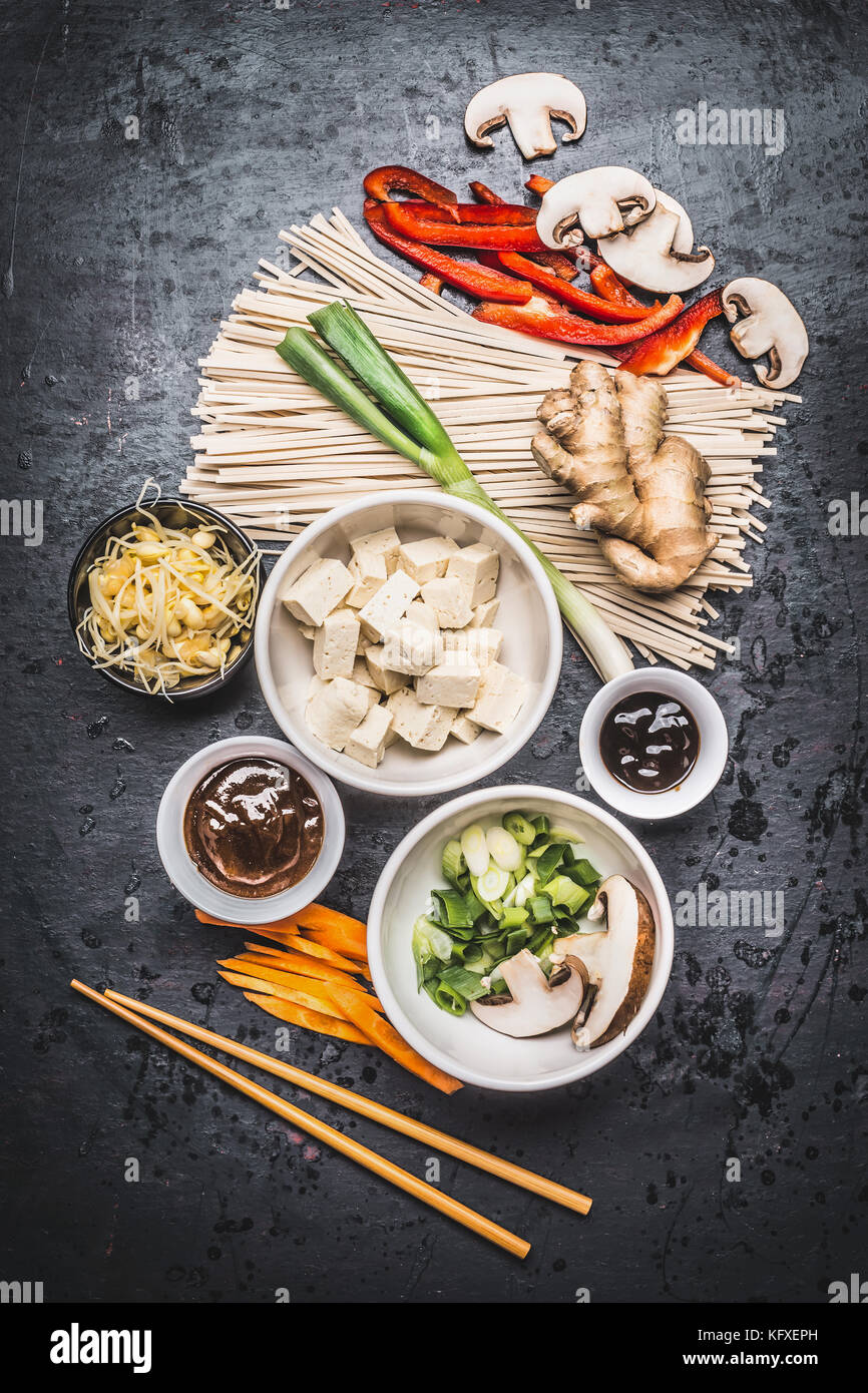 Various Asian vegetarian cooking ingredients and chopsticks with tofu, noodles, ginger, cut vegetables, Sprout,green onion ,hoisin and austern sauce o Stock Photo