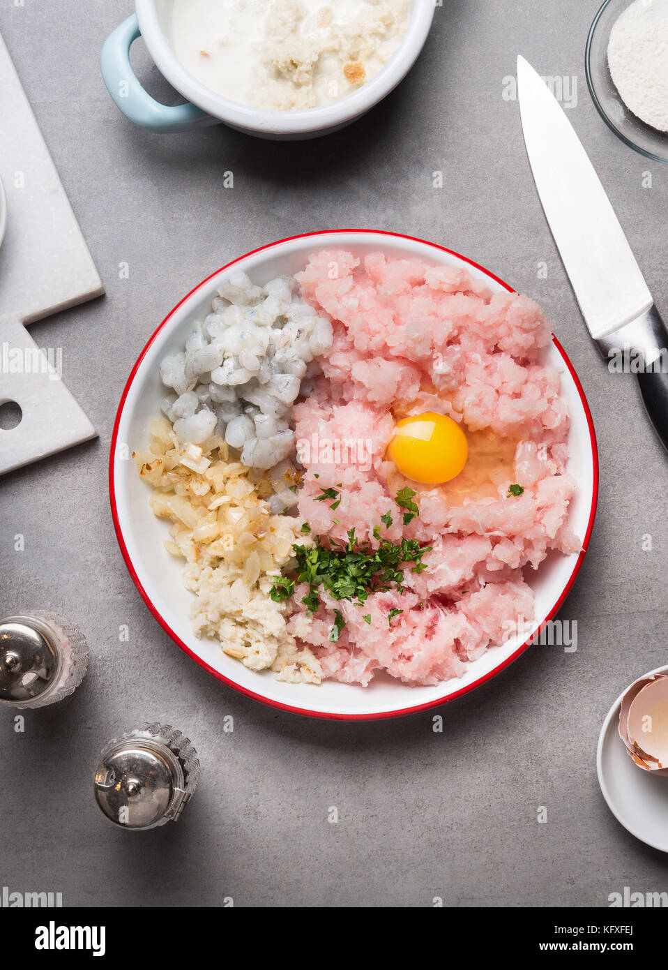 Fish patties preparation with Minced fish ,egg, shrimps , onion and soaked bread on kitchen table with knife, top view Stock Photo