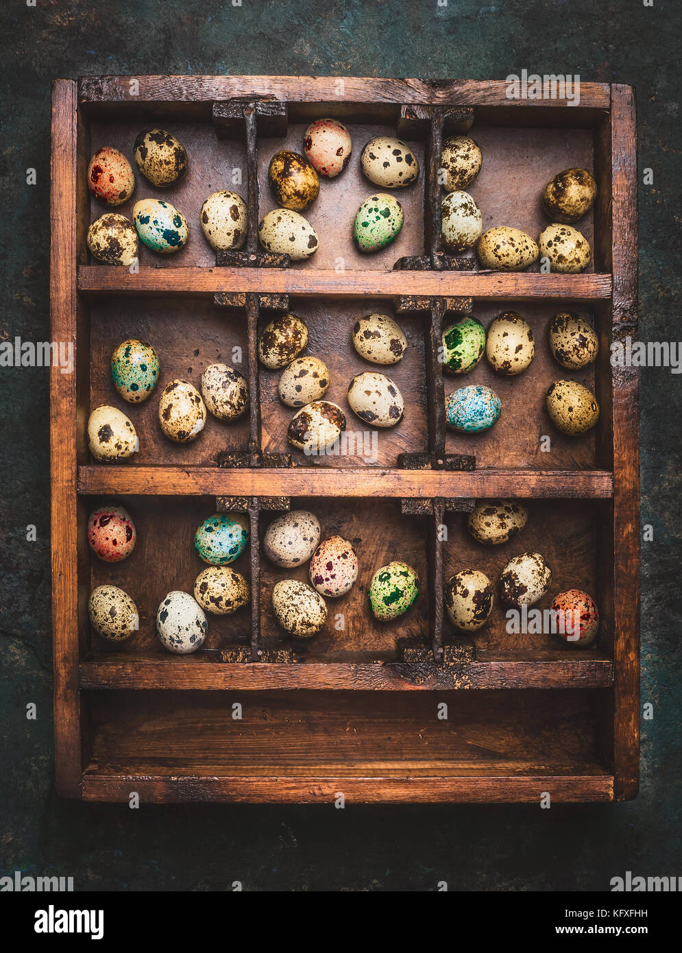 Vittage Wooden box with colorful eggs for Easter feast on dark rustic background, top view Stock Photo