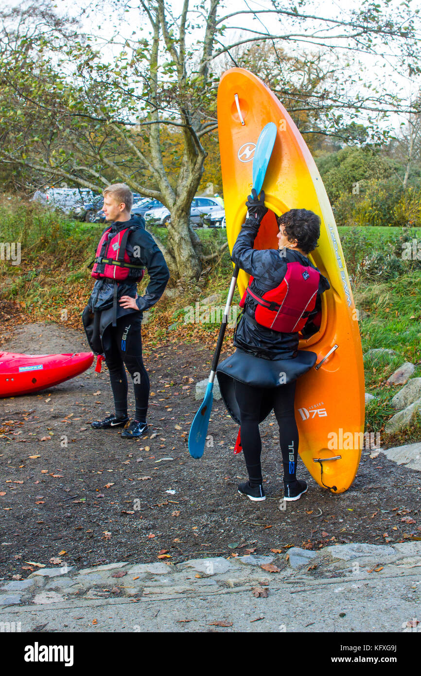 A couple of young men clearing their boating equipment after an afternoon of kayak training on the lake in Castlewellan Forest Park, Northern Ireland Stock Photo