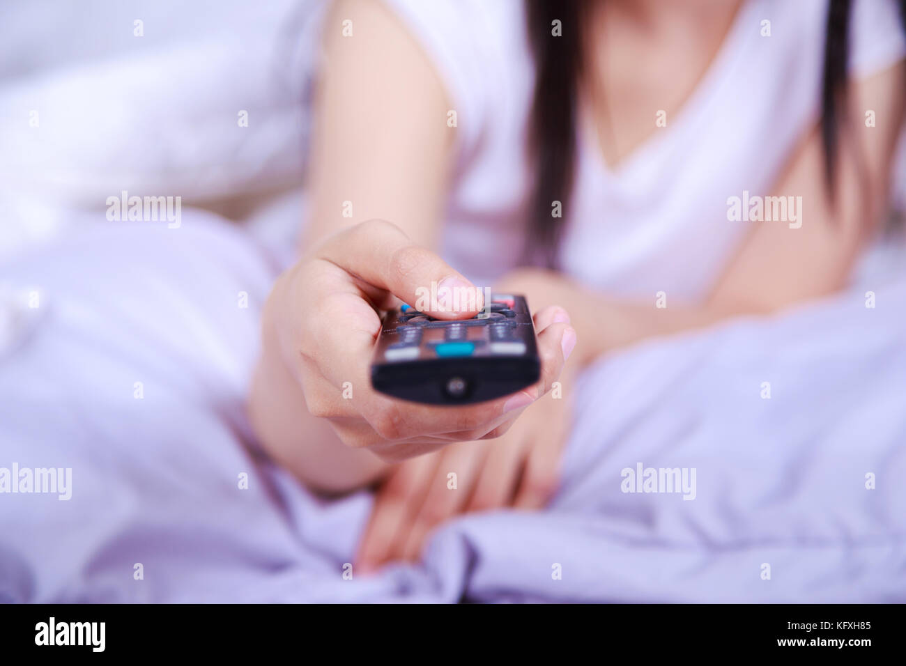 close up tv remote control on hand of woman on the bed Stock Photo