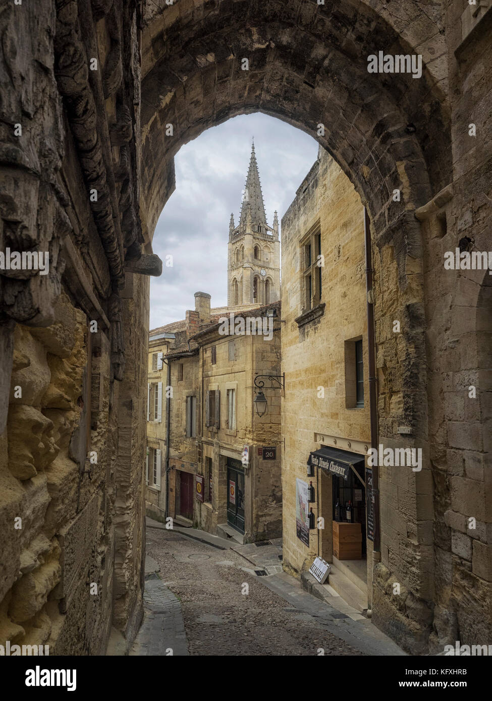 SAINT-EMILION, FRANCE - SEPTEMBER 07, 2017:  View through arched gate in town waslls to the Spire of the Monolithic Church rising above the village Stock Photo