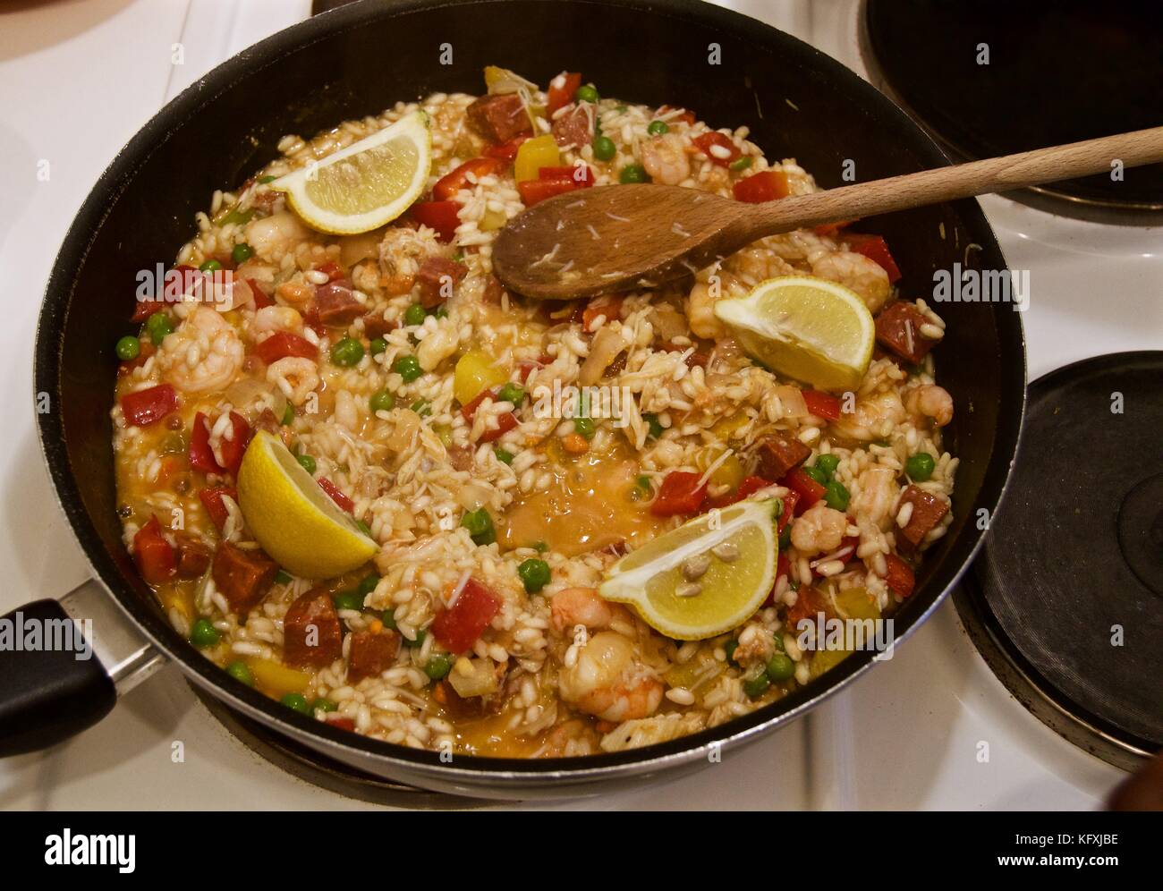 Cooking a seafood paella on the hob in a teflon coated wok with wooden  spoon Stock Photo - Alamy