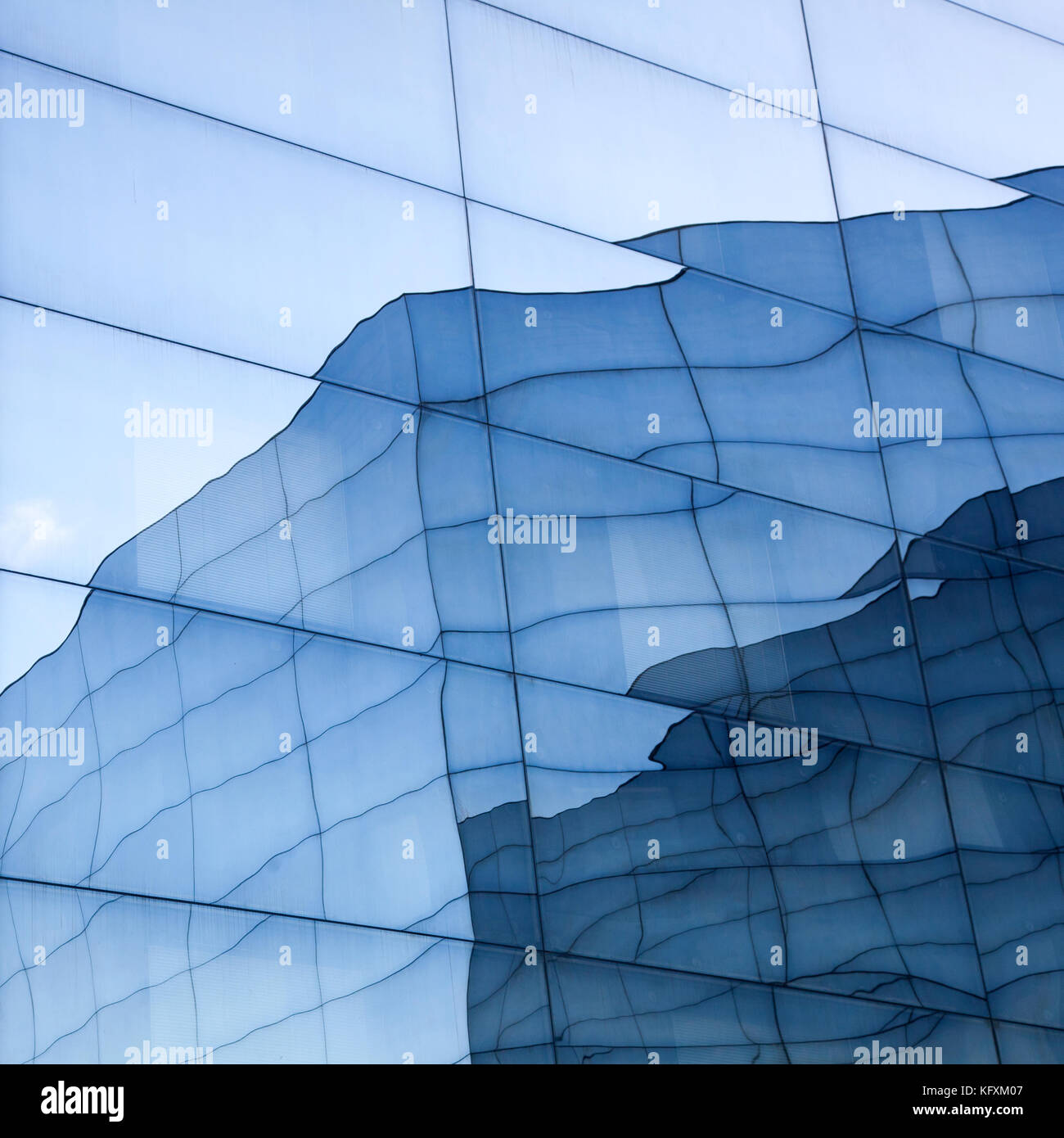 facade of modern glass building with reflections of blue sky and glass ...