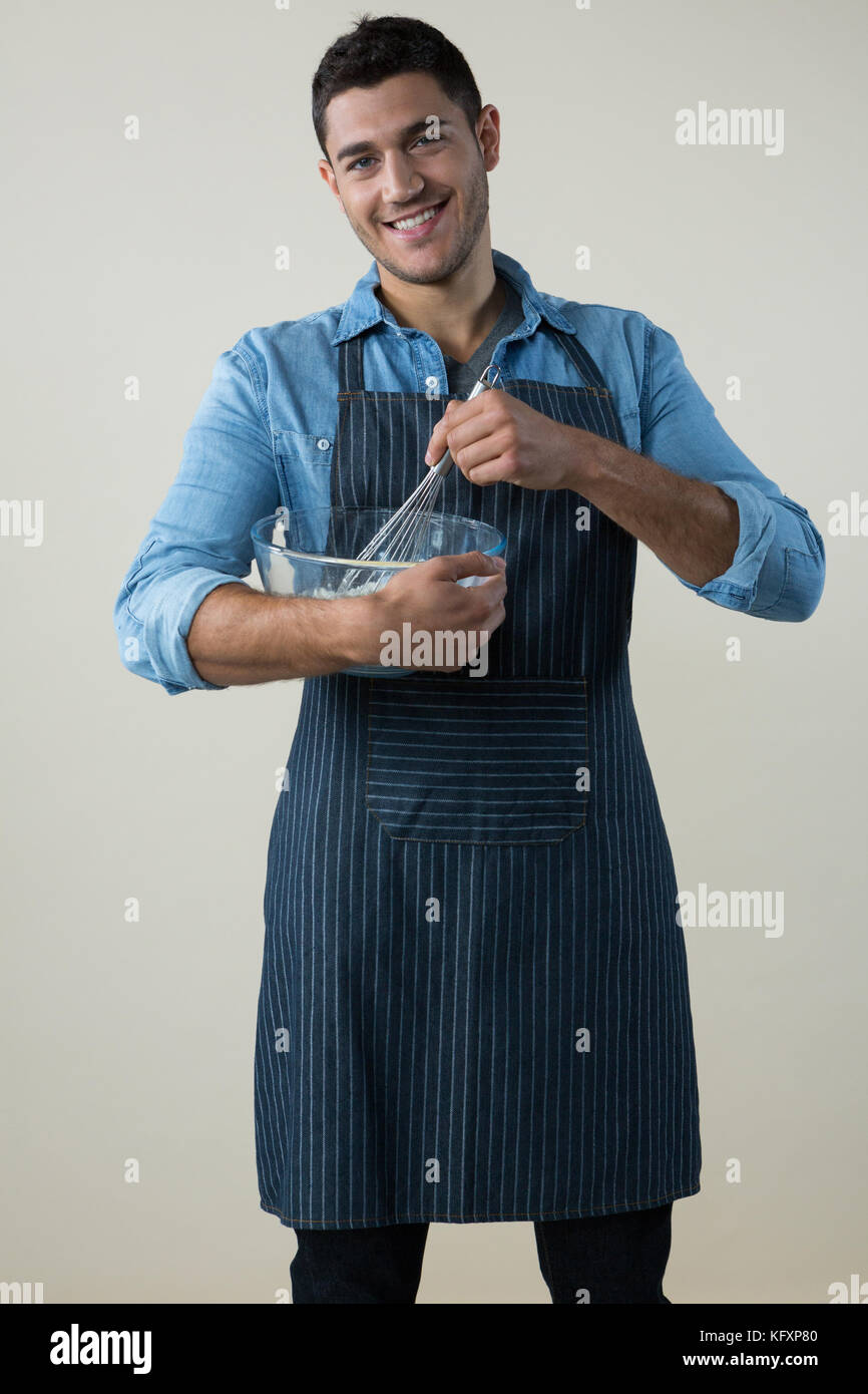Smiling chef holding a whisk in the bowl Stock Photo - Alamy