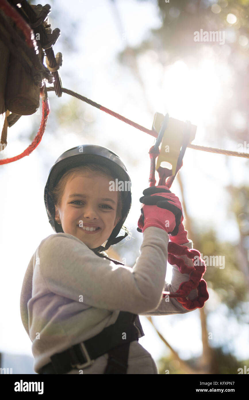 Smiling cute girl enjoying zip line adventure on sunny day Stock Photo
