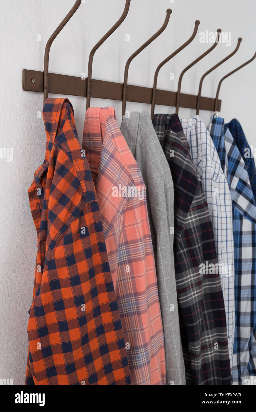 Close-up of various shirts hanging on hook against white wall Stock Photo -  Alamy