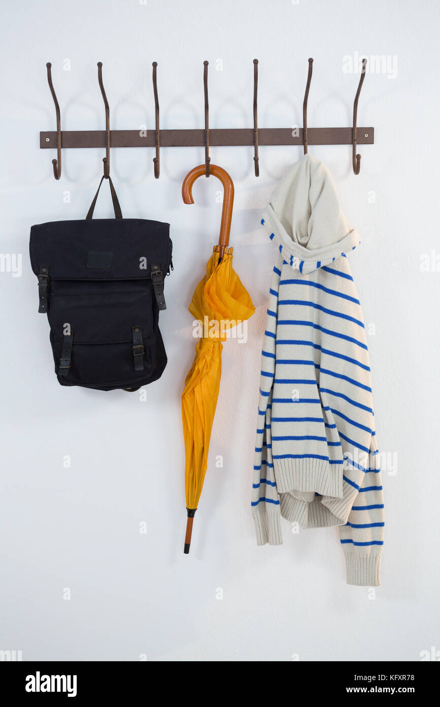 Close-up of hoodie, umbrella and bag hanging on hook Stock Photo