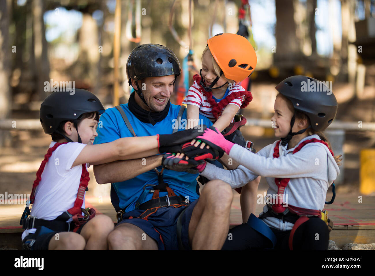 Smiling instructor and kids forming hand stack in park Stock Photo - Alamy
