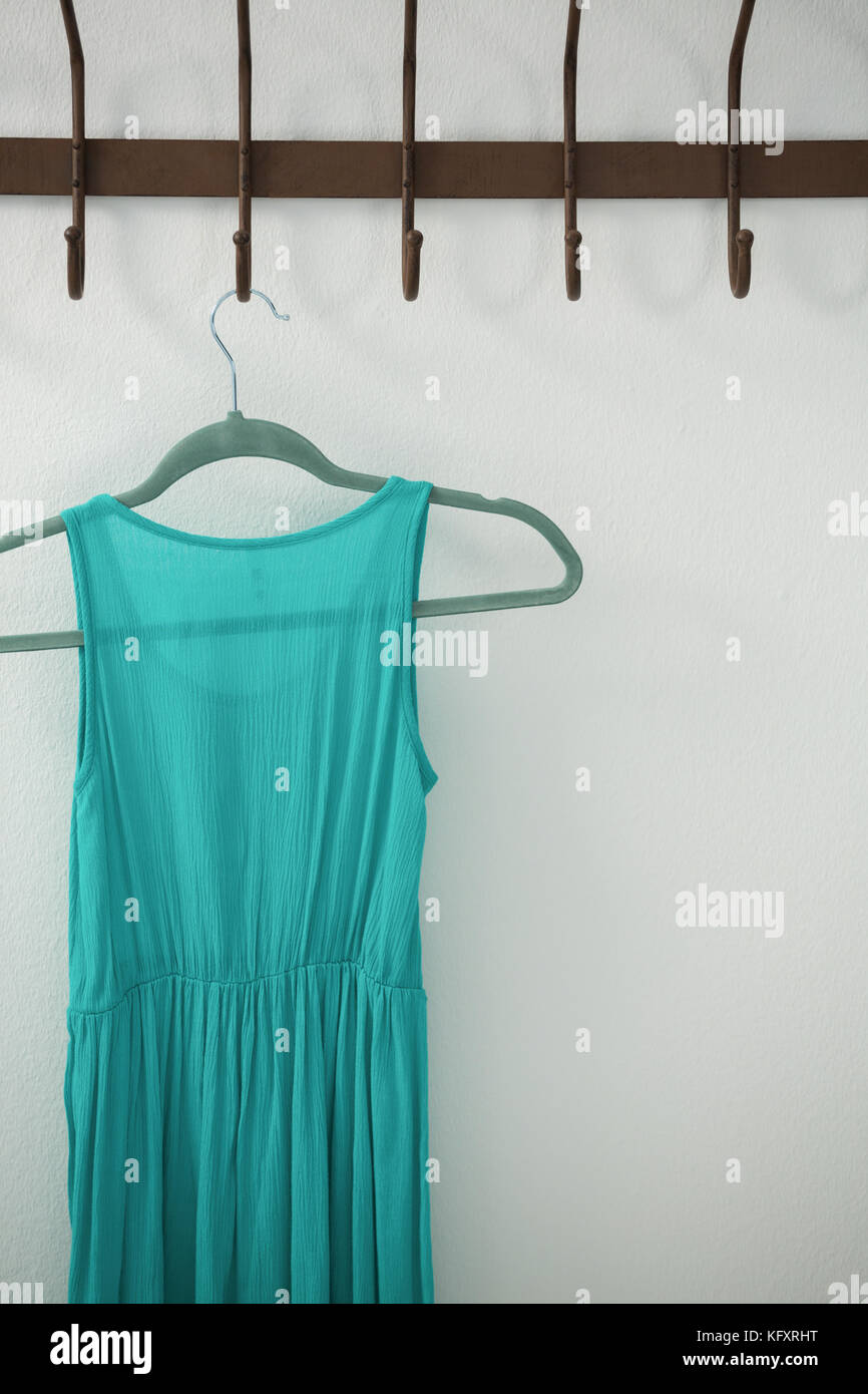 Close-up of turquoise dress hanging on hook against white wall Stock ...