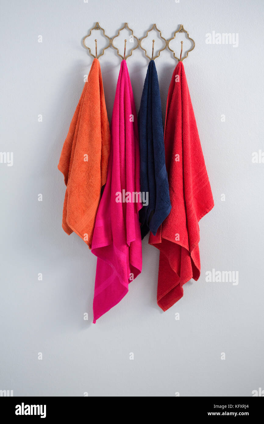 Colorful towels hanging on hook against white wall Stock Photo Alamy