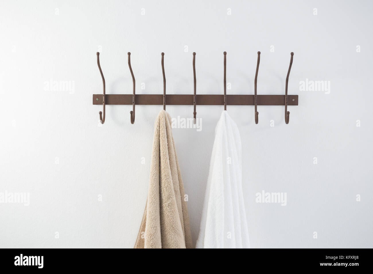 Towels hanging on hook against white wall Stock Photo Alamy
