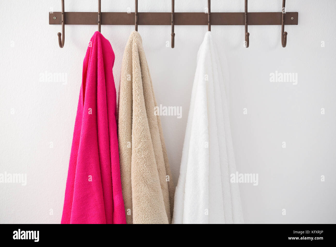 Colorful towels hanging on hook against white wall Stock Photo Alamy