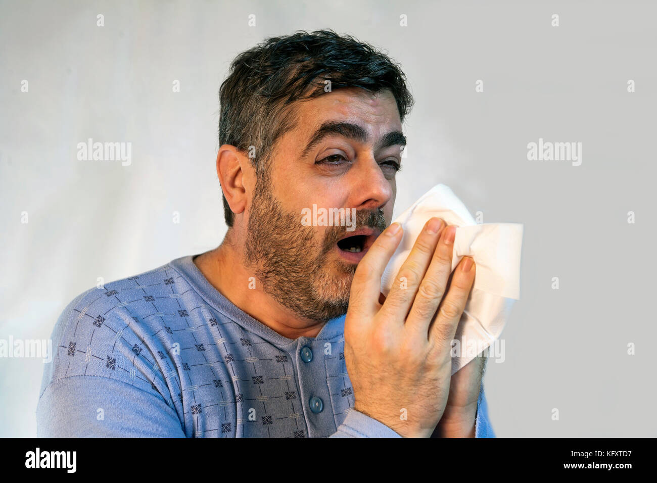 Man medium-sized age in pajamas sneezing with a strong cold Stock Photo
