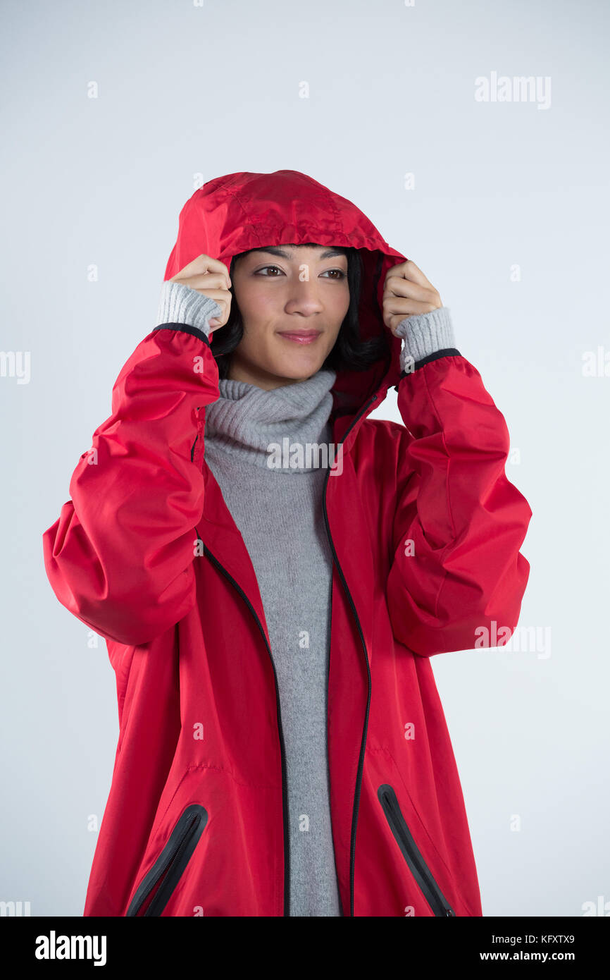 Smiling woman in hooded jacket standing against white background Stock Photo
