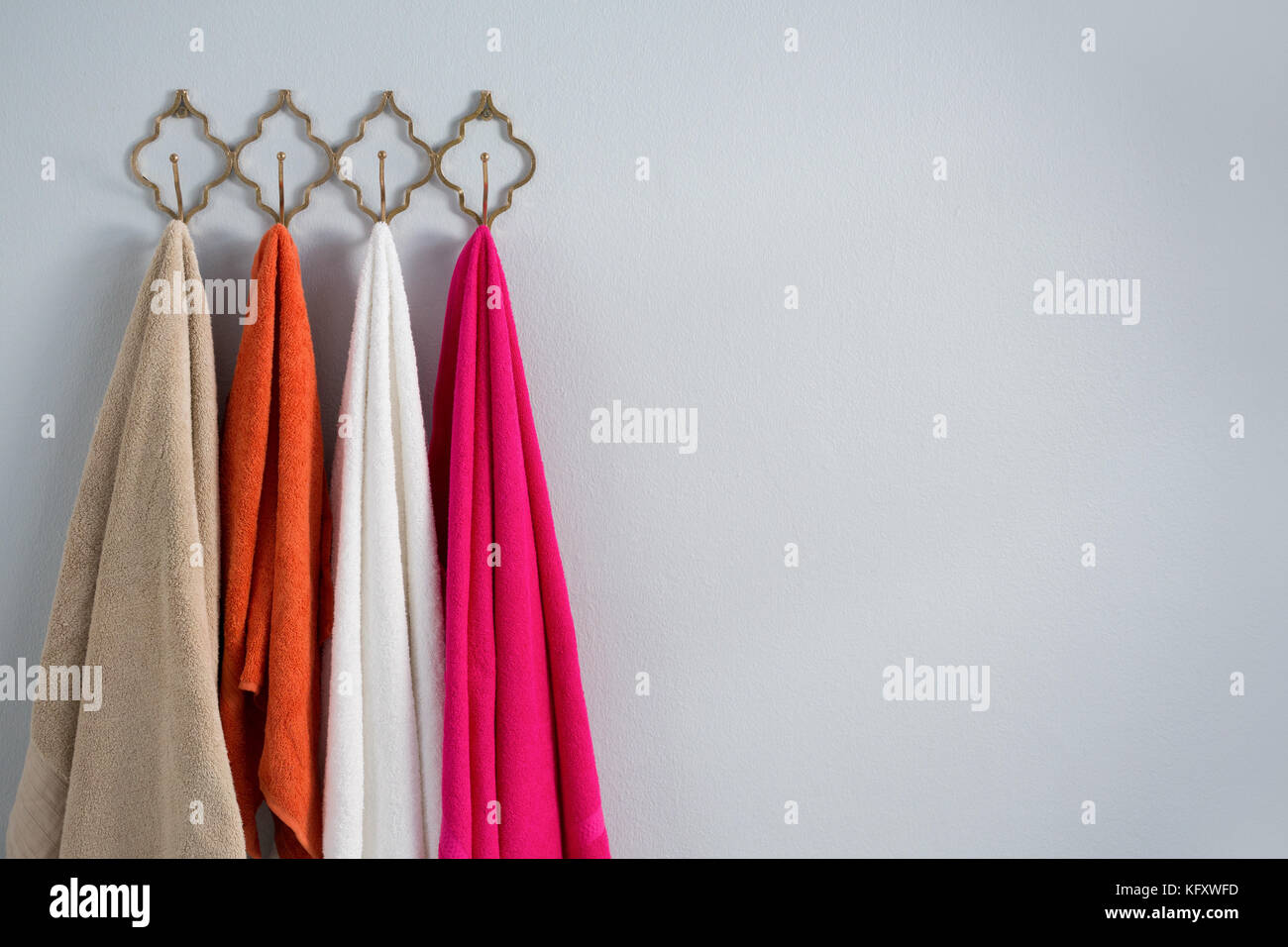 Colorful towels hanging on hook against white wall Stock Photo Alamy