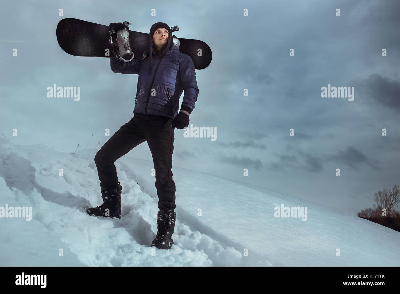 Young snowboarder standing on hill and holding board for snowboarding. Stock Photo