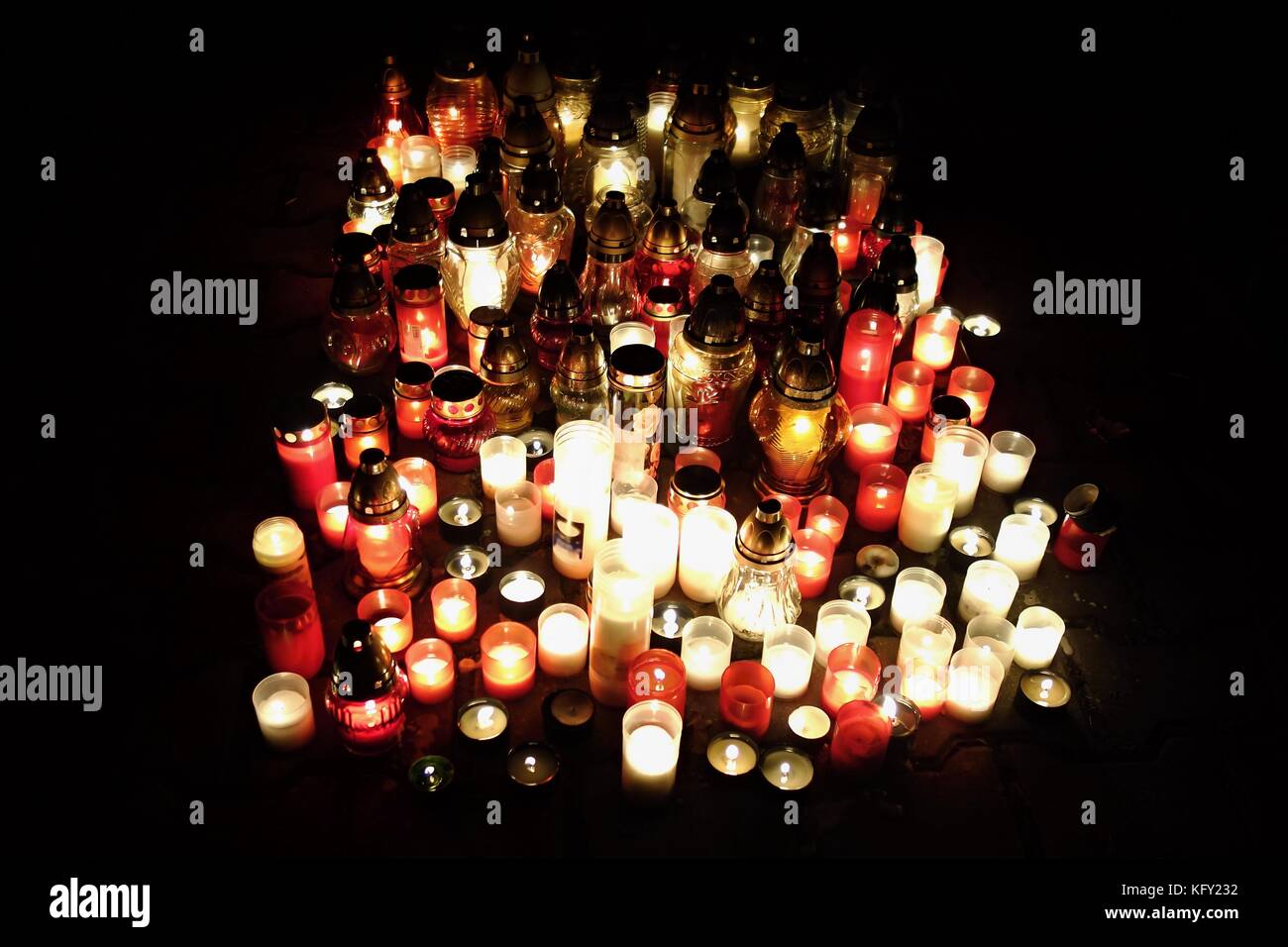 Votive candles lantern burning on the graves in cemetery at night time
