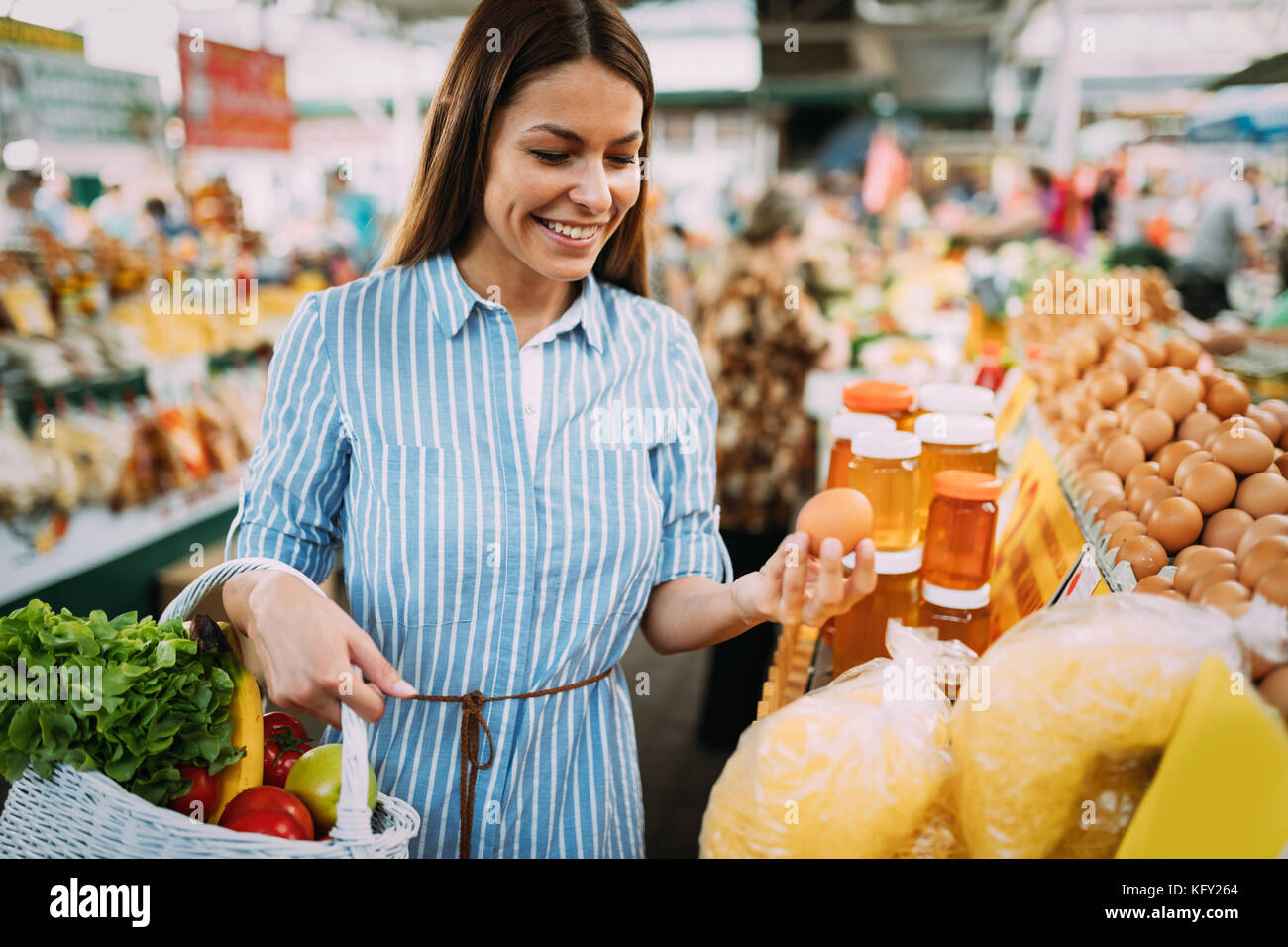 Portrait of beautiful woman holding shopping basket at marketplace ...