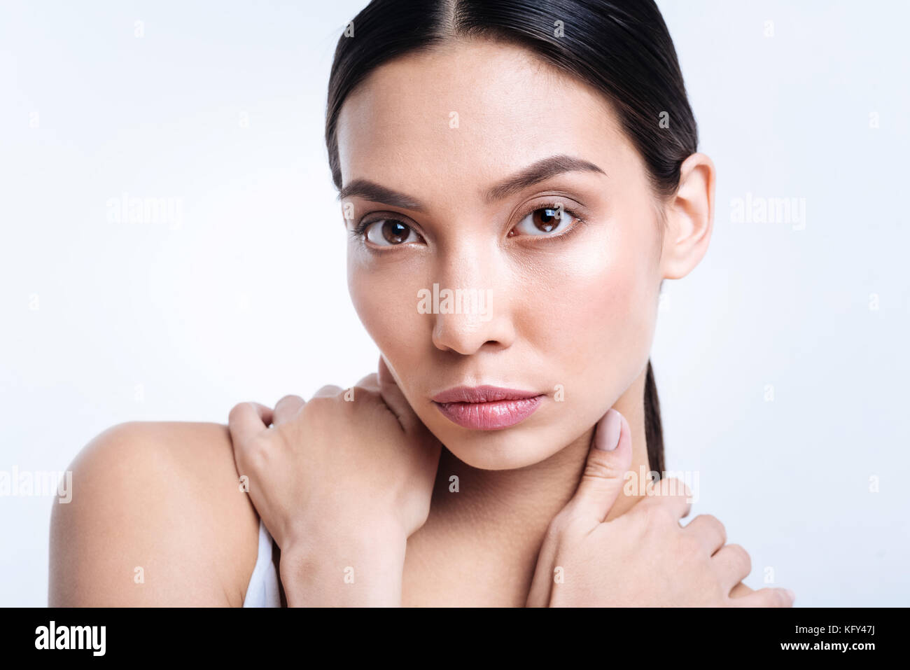 Attractive brunette holding her hands near neck Stock Photo - Alamy