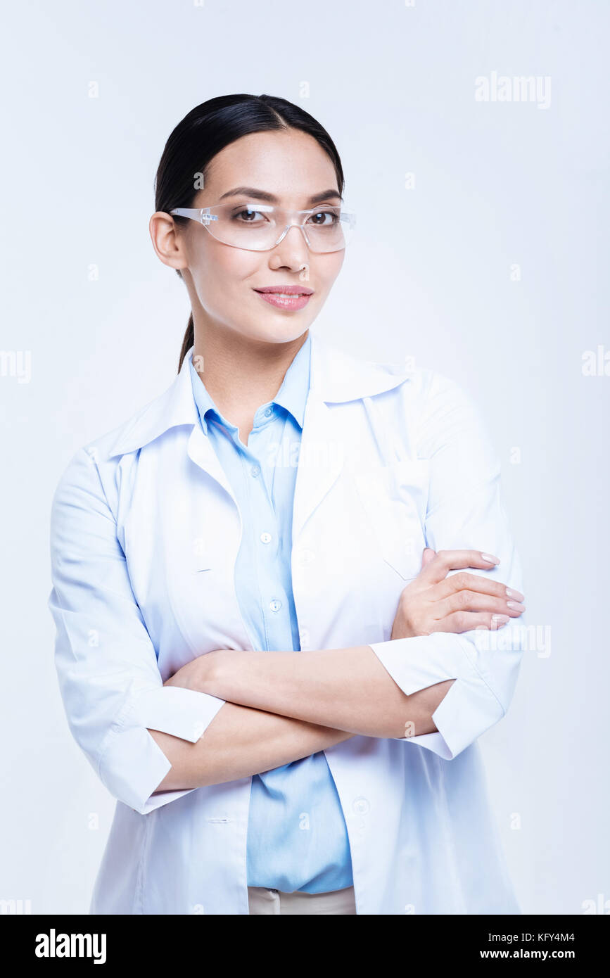 Cheerful lab worker in safety glasses posing against white background