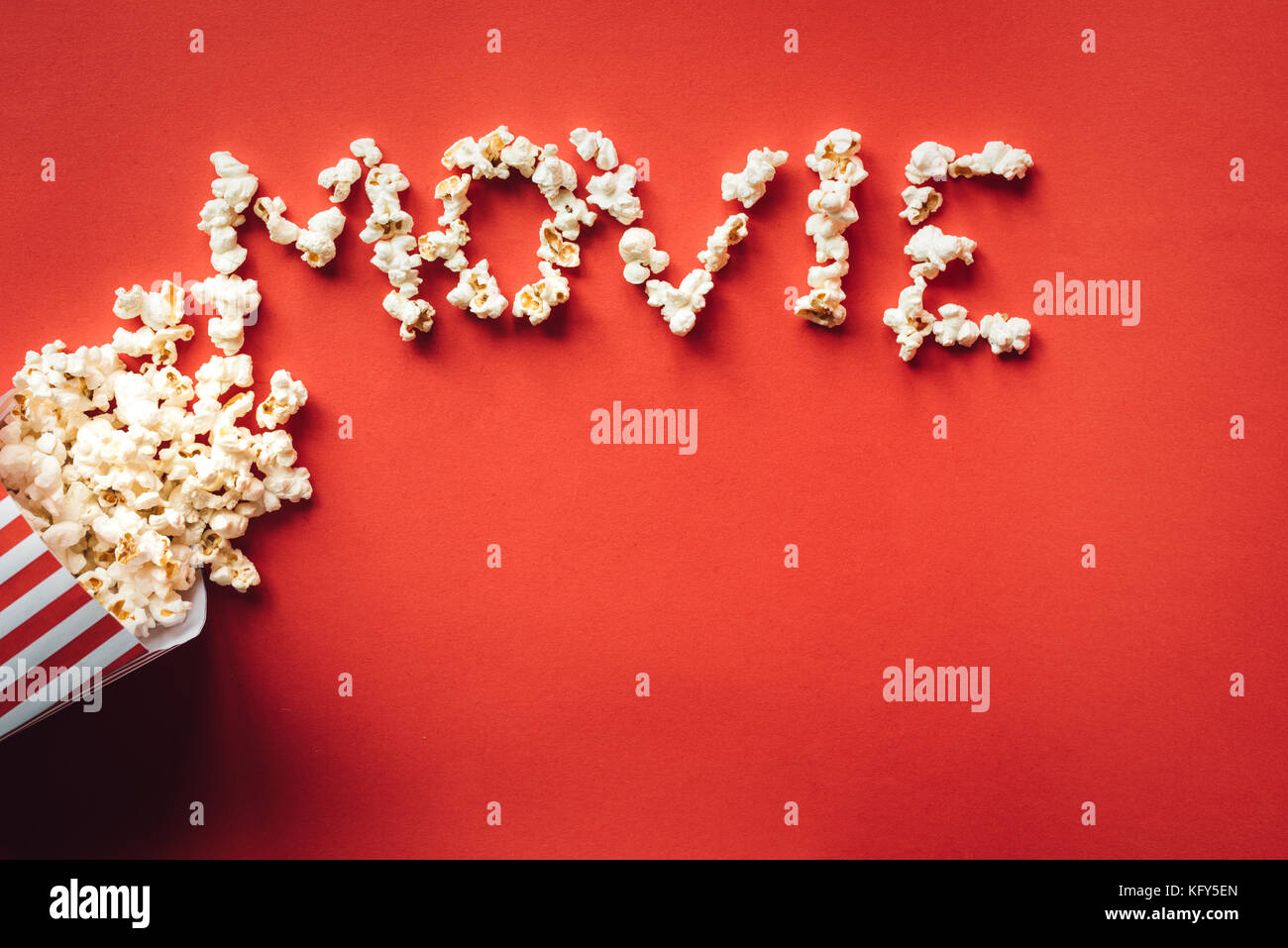 Striped box with popcorn and word Movie on red background Stock Photo