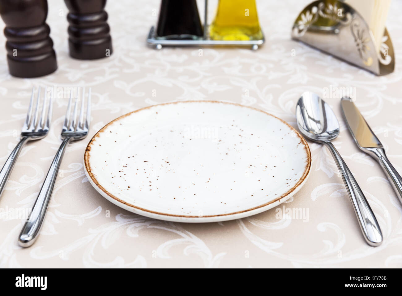 Table setting with plates, knife, fork and spoon, restaurant interior