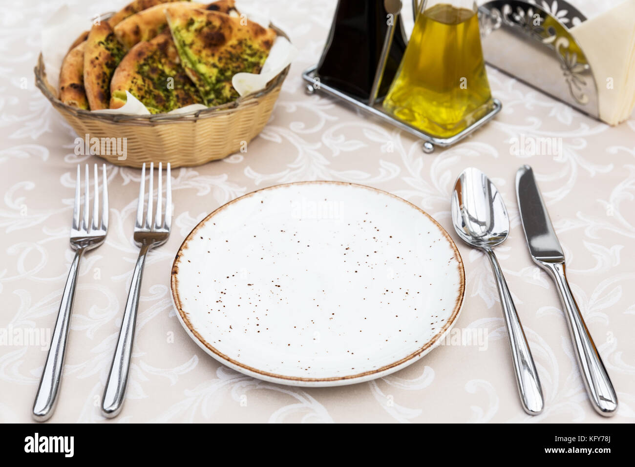 Table setting with plates, knife, fork and spoon, restaurant interior