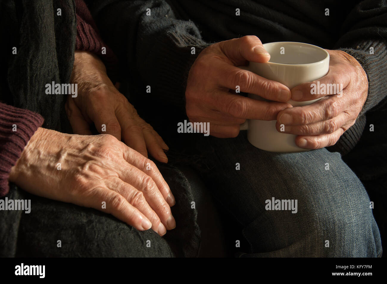 Hands of an old woman and an old man holding a mug Stock Photo