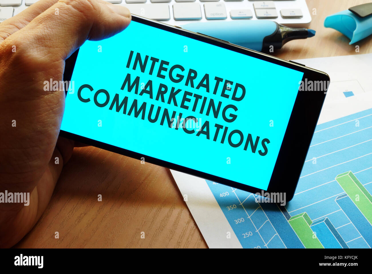 Hand holding smartphone with words integrated marketing communications. Stock Photo