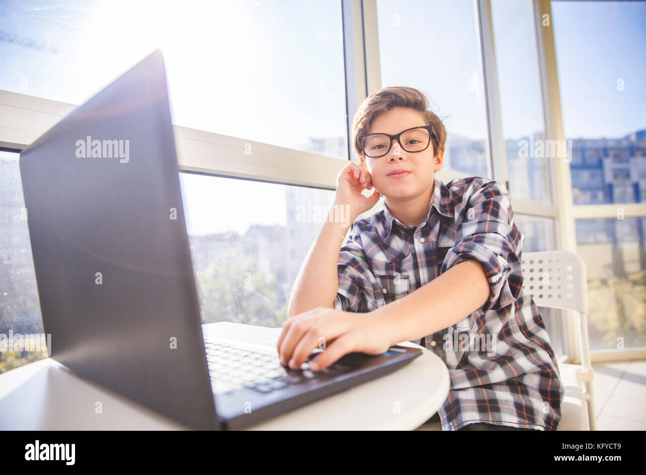Portrait of teen boy using laptop by window Stock Photo - Alamy