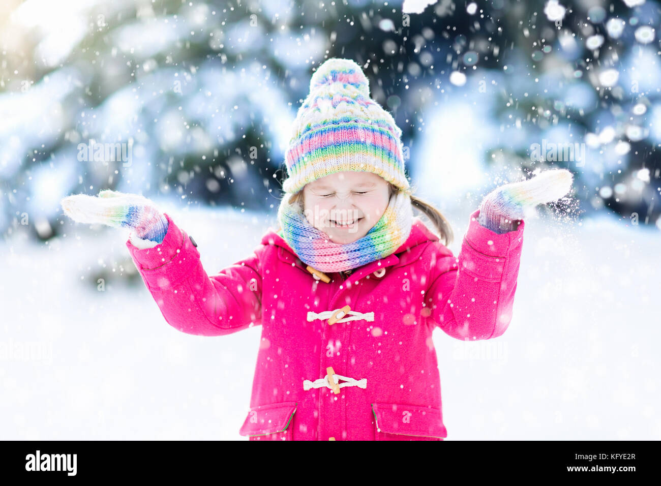 Child playing with snow in winter. Little girl in colorful jacket and ...