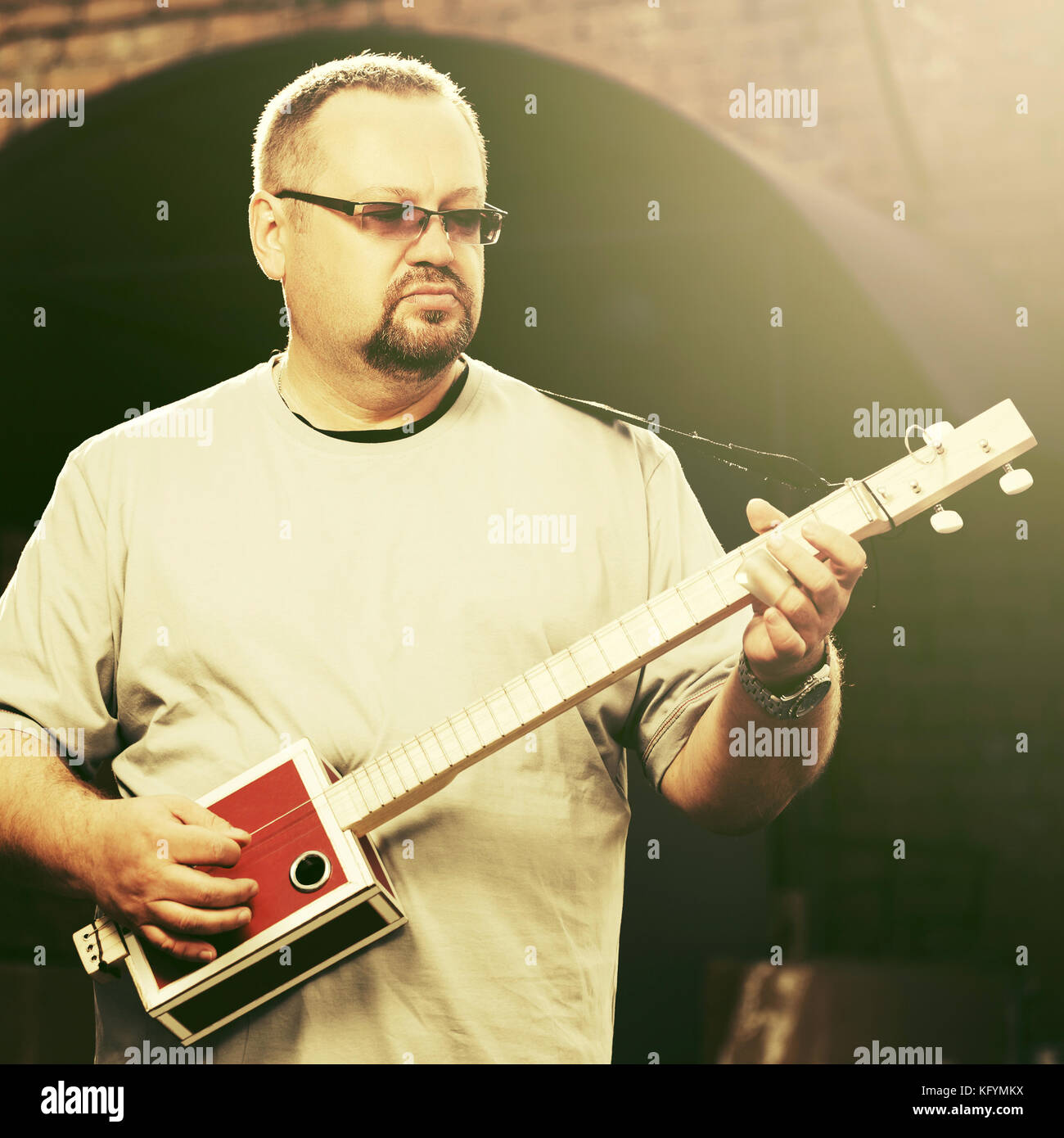 Handsome man playing his cigar box guitar Stock Photo