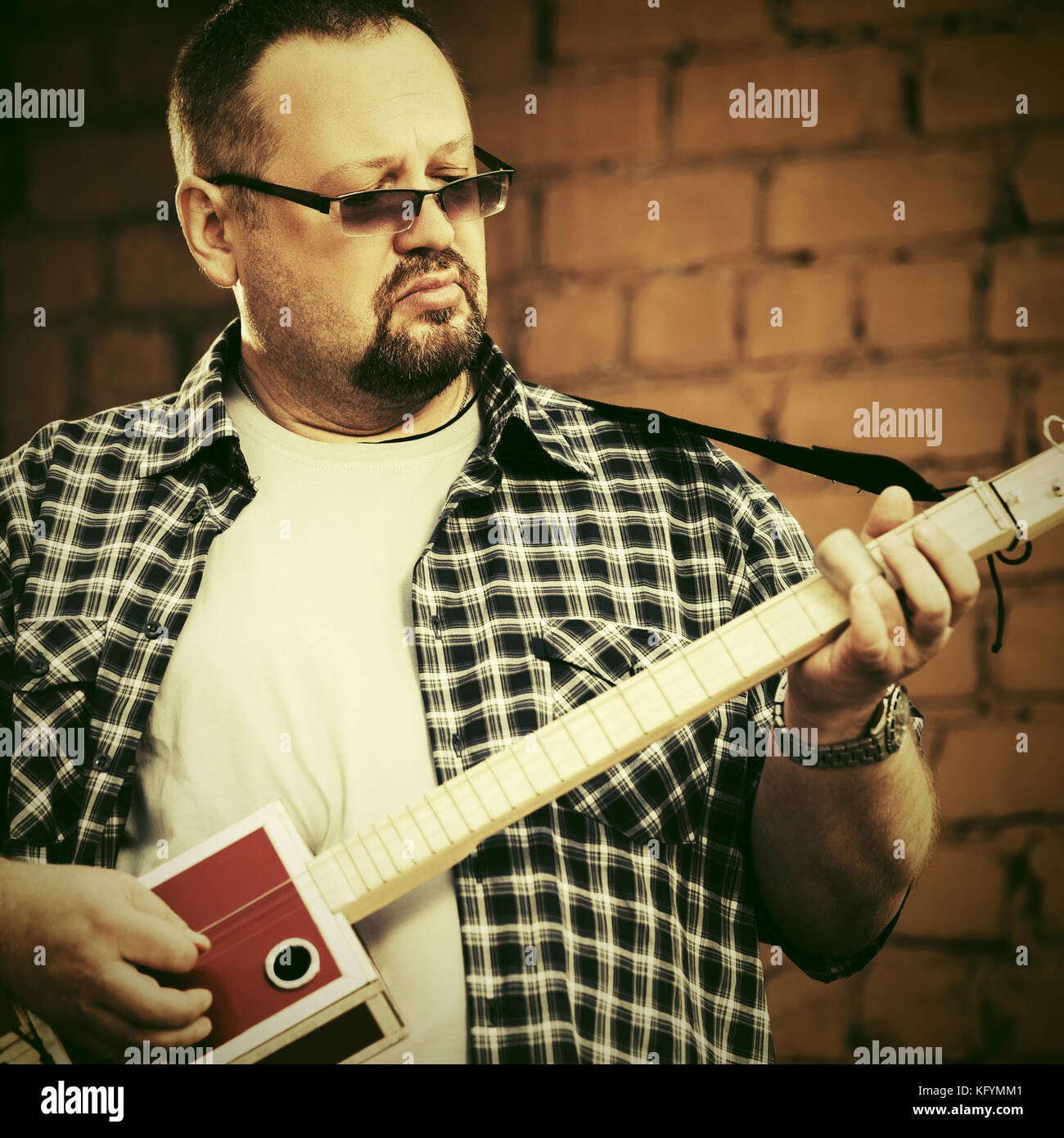 Handsome man playing his cigar box guitar Stock Photo