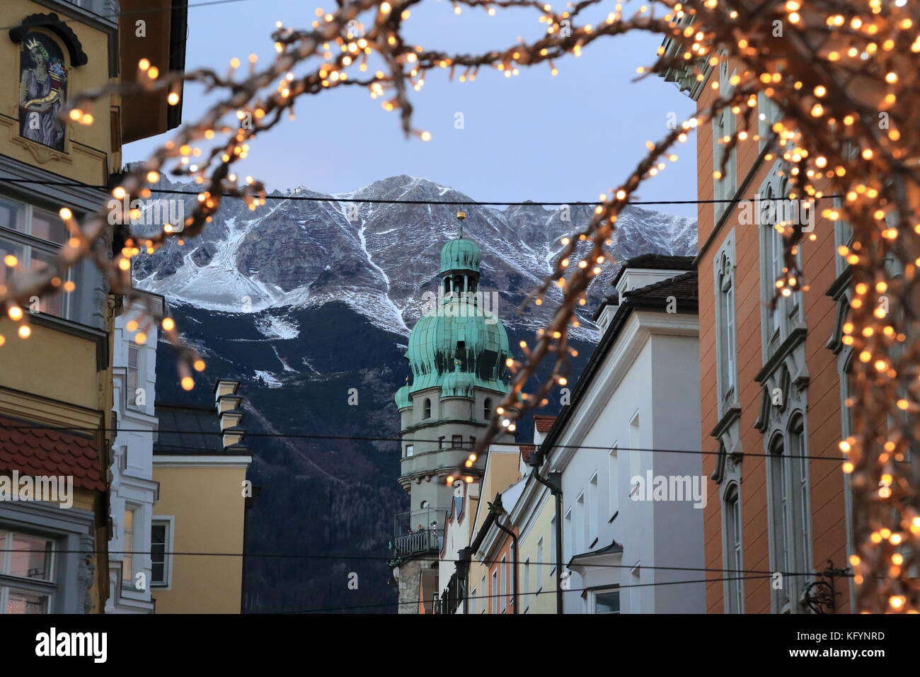 Roofs of Innsbruck with mountains on a background and Christmas lights on a foreground at evening Stock Photo