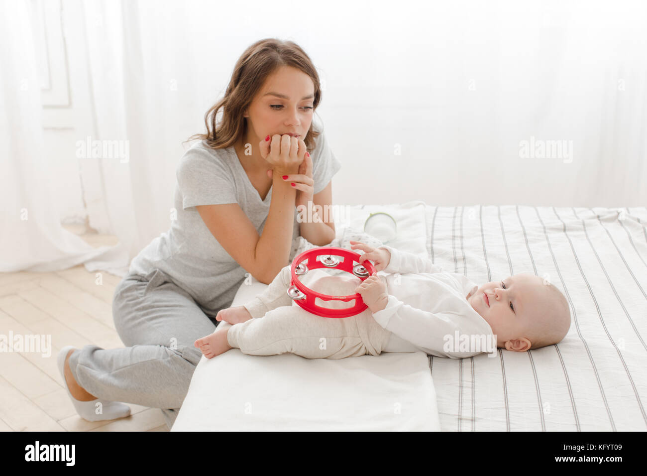 Pensive mother with baby in bedroom Stock Photo