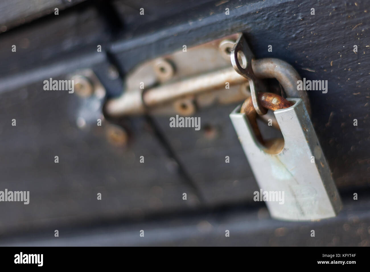 a locked rusty padlock on a sliding bolt latch in the lock position on